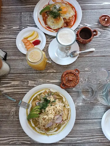 Mesa con dos desayunos, jugos, fruta y huevos con salsa